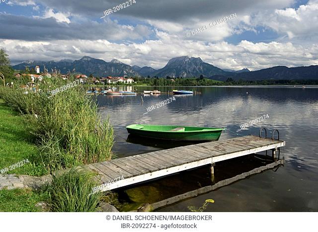 A wooden jetty and a boat on lake Hopfensee near Fuessen, Allgaeu, Bavaria, Germany, Europe