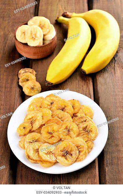 Chips and fresh bananas on wooden table