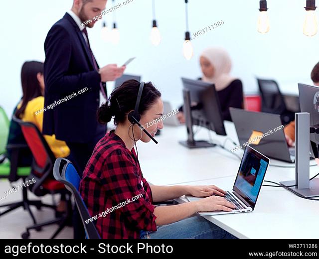 businesswoman in office giving support speaking over headset at modern startup coworking open space