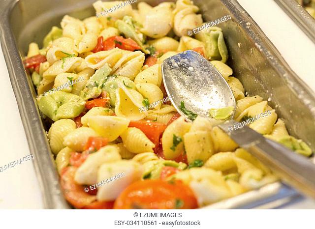Fresh pasta salad with tomatoes in serving tray at salad bar