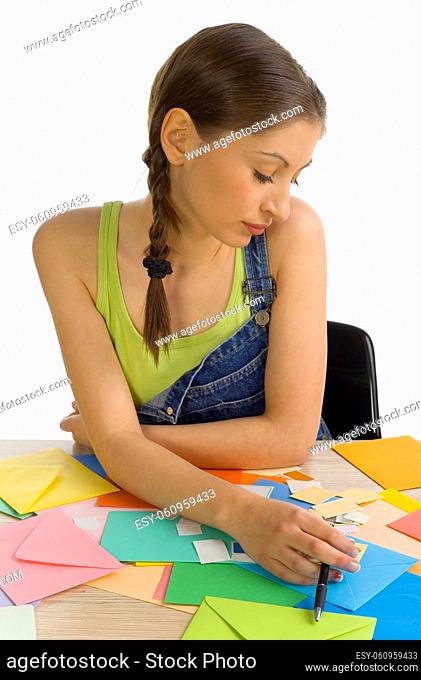 Young, beautiful, sad woman sitting and writing a letter. Thinking of something, front view. White background