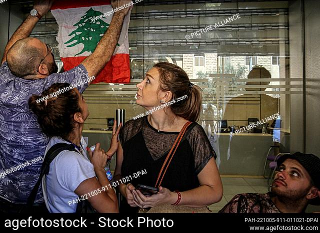 05 October 2022, Lebanon, Beirut: Lebanese activists and supporters of Lebanese lawmaker Cynthia Zarazir hang up the national flag of Lebanon outside a branch...