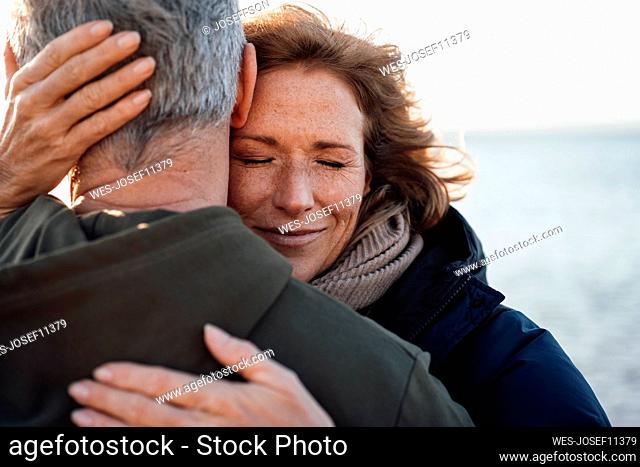Smiling mature woman embracing man at vacation