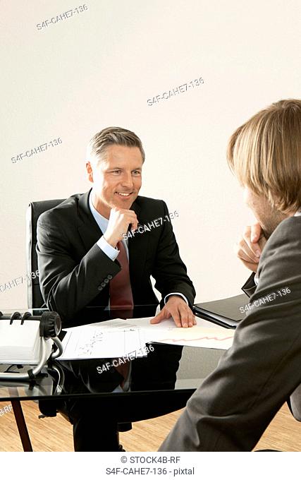 Two businessmen at desk talking