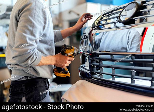 Auto mechanic holding power tool working in workshop