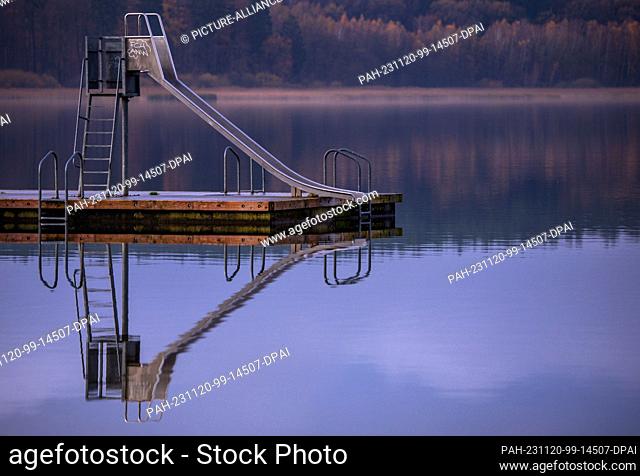 20 November 2023, Mecklenburg-Western Pomerania, Warin: A water slide stands on a jetty in the lido and is reflected in the water of the Großer Wariner See