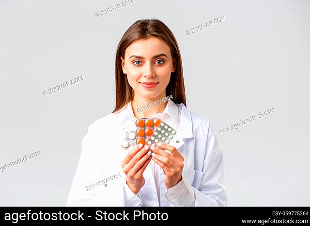 Covid-19, preventing virus, health, healthcare workers and quarantine concept. Physician in medical white scrubs, attractive female doctor showing medicine
