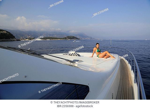 Young woman wearing a green bikini sitting on the front sun deck of a motor yacht, French Riviera, Cote d'Azur, Mediterranean Sea, Europe