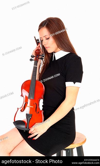 A beautiful woman sitting in a black dress holding her violin resting with her eyes closed, isolated for white background