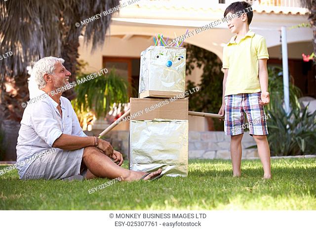 Grandfather And Grandson Building Model Robot In Garden