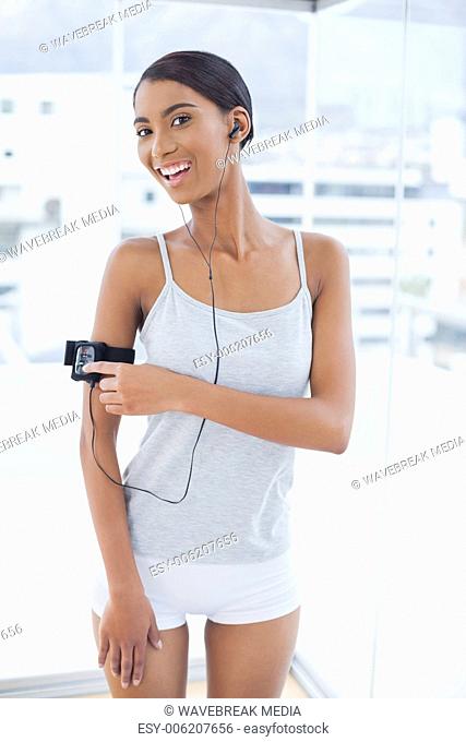 Smiling pretty model in sportswear changing song on her mp3