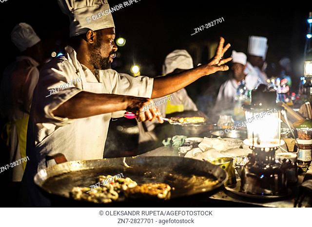 Chefs prepare dishes during the Night food market at Forodhani Gardens in Stone Town, Zanzibar City, Zanzibar, Tanzania. This street food includes different...