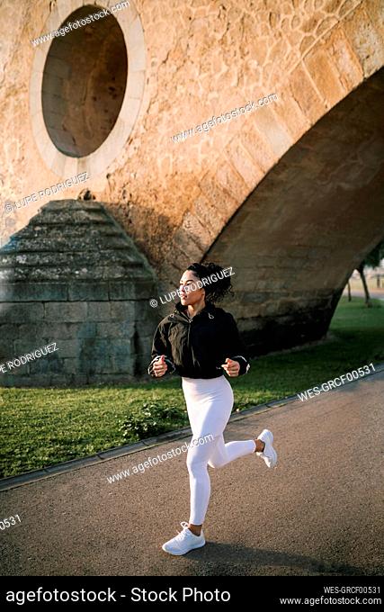 Sportswoman jogging on footpath in public park