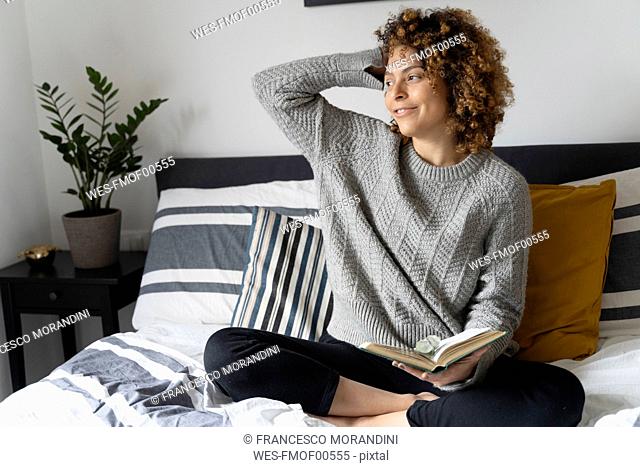Woman sitting on bed, reading book