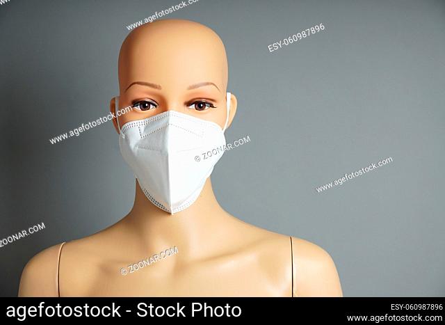 a shop window mannequin or display dummy head wearing FFP2 face maskas shopping hygiene concept