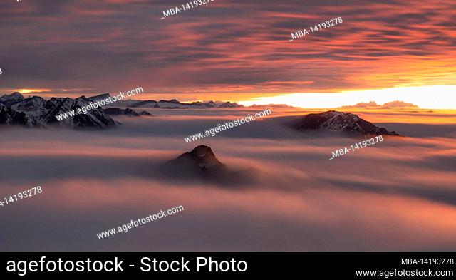 Dramatic sunset in the mountains. View from the summit of Aggenstein over the clouds to Säntis. Allgäu Alps, Bavaria, Germany, Europe