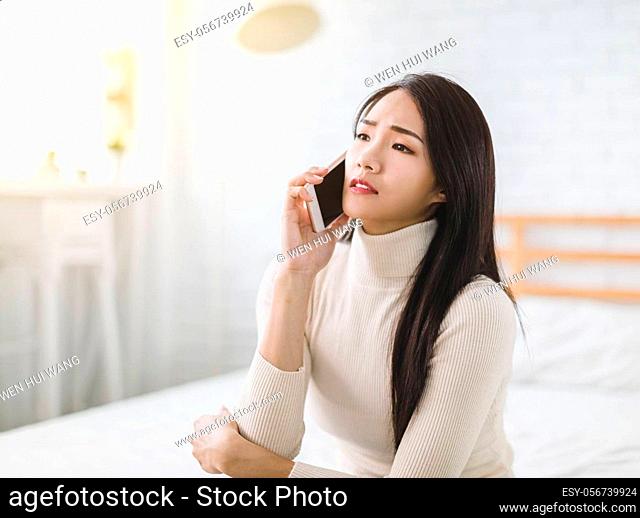 unhappy young woman talking on mobile phone at home