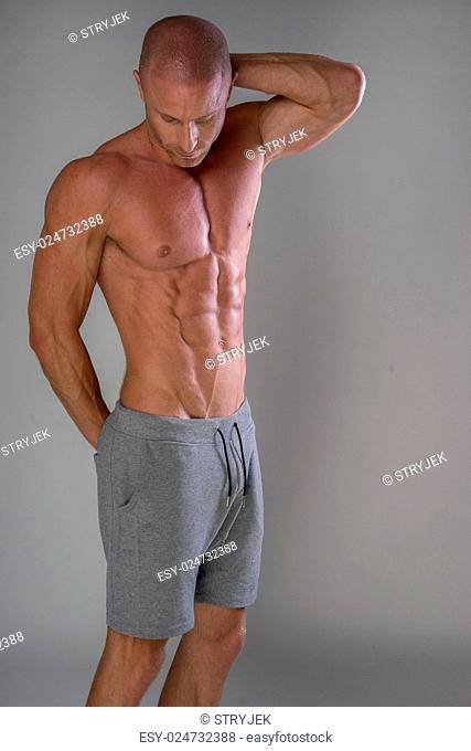 Handsome muscular man shirtless wearing grey pants