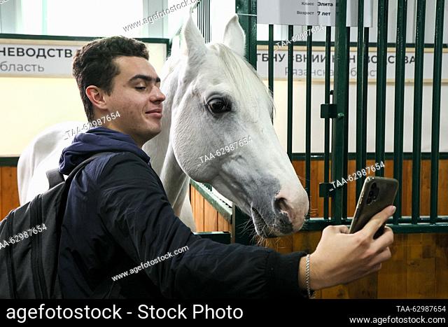 RUSSIA, MOSCOW - OCTOBER 4, 2023: A man takes a selfie with a horse at the 2023 Golden Autumn agricultural exhibition held at the Russian State Agrarian...