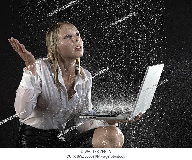 Businesswoman using laptop in rain