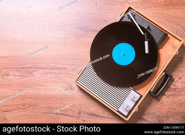 Older Gramophone with a vinyl record on wooden table, top view and copy space, photo