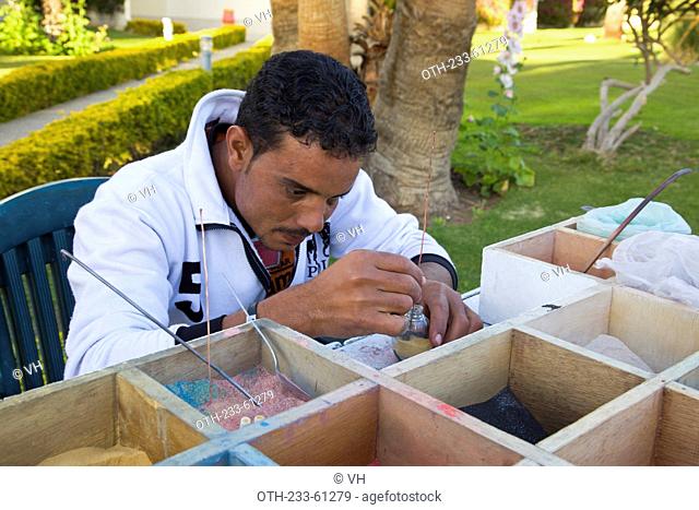 A vendor arranging the sand bottle souvenir for sale at the garden of Hilton resort hotel, Hurghada, Egypt