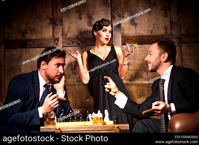 Focus on elegant lady with red lips. Rivalry or competition between two businessmen fighting for woman while playing chess