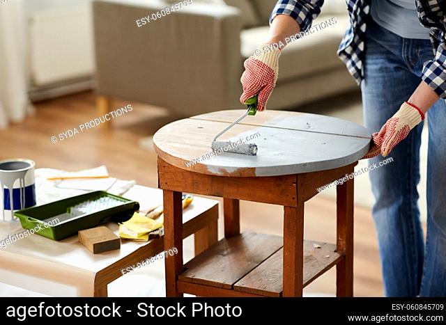 woman painting old wooden table in grey color
