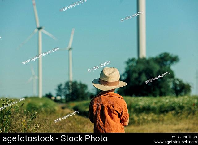 Boy wearing hat standing in field on sunny day