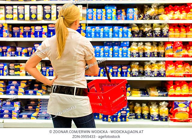 Eine Frau ist mit der großen Auswahl in einem Supermarkt beim Einkauf überfordert