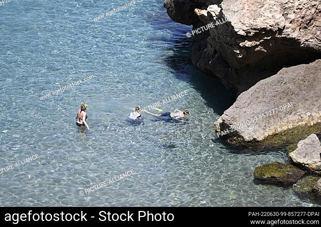 29 June 2022, Spain, Deia: People swimming on the rocky beach Cala Deia in Mallorca. Photo: Clara Margais/dpa. - Deia/Mallorca/Spain
