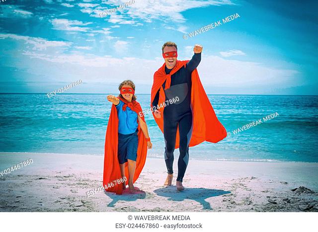 Cheerful father and son in superhero costume with hand raised