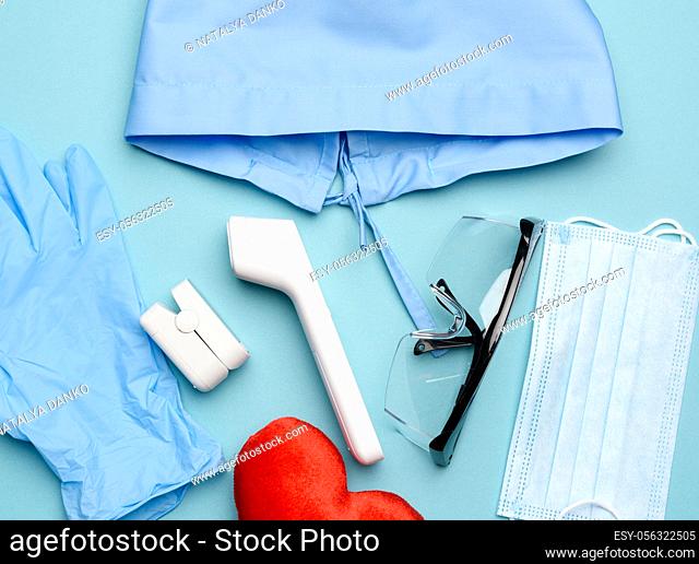 pulse oximeter and electronic thermometer and other medical supplies on a blue background, top view