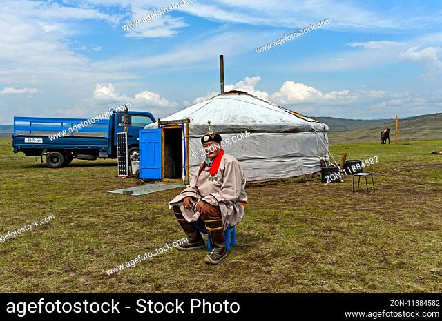 Älterer Nomade in traditioneller Kleidung sitzt vor seiner Jurte, Mongolei / Elderly male nomad in traditional dress sitting in front of his yurt, Mongolia