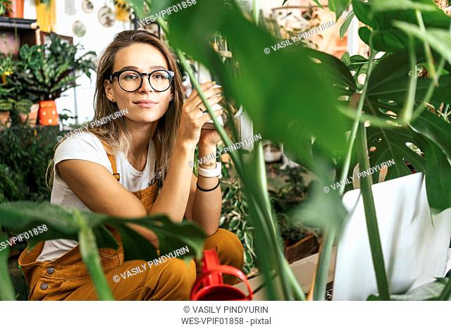 Portrait of a young woman having a coffee break in a small gardening shop