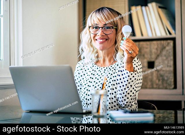 Happy woman having an idea at work place. Cheerful female smile for a solution while work at the desk in the office with a laptop