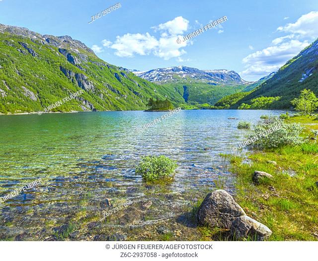 Lake Roldalsvatnet in Norway, with small island and view to village Boten and snow capped mountains, Roldal in Norway, Scandinavia