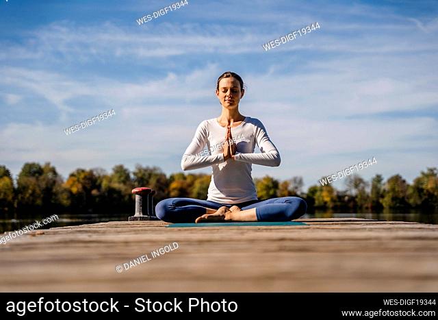 Woman with hands clasped sitting on jetty