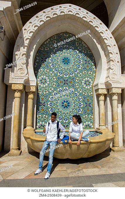 Moroccan teenagers taking photos at a fountain at the Hassan II Mosque or Grande Mosquee Hassan II in Casablanca, which is the largest mosque in Morocco and...