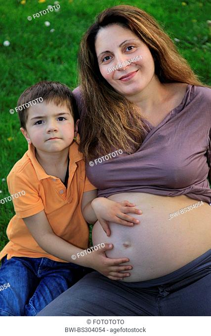 little boy stroking the belly bump of his mother