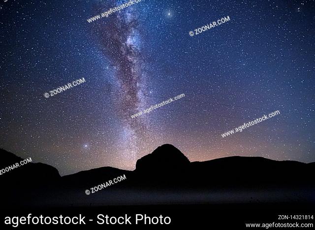 Billions of stars forming the Milky Way shining brightly overhead the Capertee Valley with a pre dawn glow on the horizon and a light mist over the land