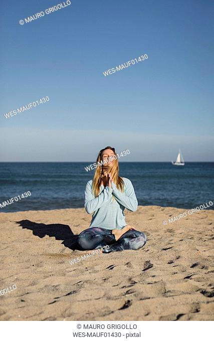 Woman doing yoga on the beach, lotus position
