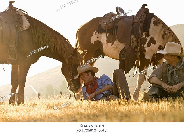 Two cowboys resting with their horses