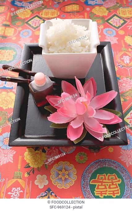Rice, soy sauce and chopsticks on tray Asia
