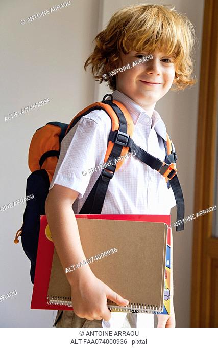 Boy prepared for school, carrying backpack and notebooks