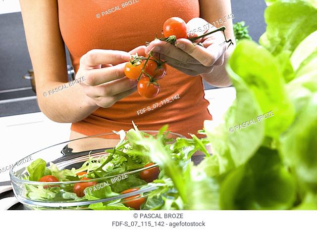 Mid section view of a woman holding bunch of tomatoes in her hands