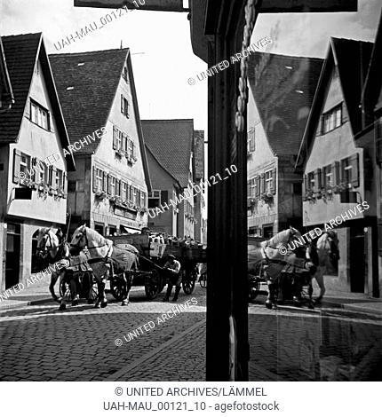 Die Szene, wie ein Mann sein Pferdefurhwerk einlenkt, spiegelt sich in der Schaufensterscheibe eines Geschäfts in Dinkelsbühl, Deutschland 1930er Jahre