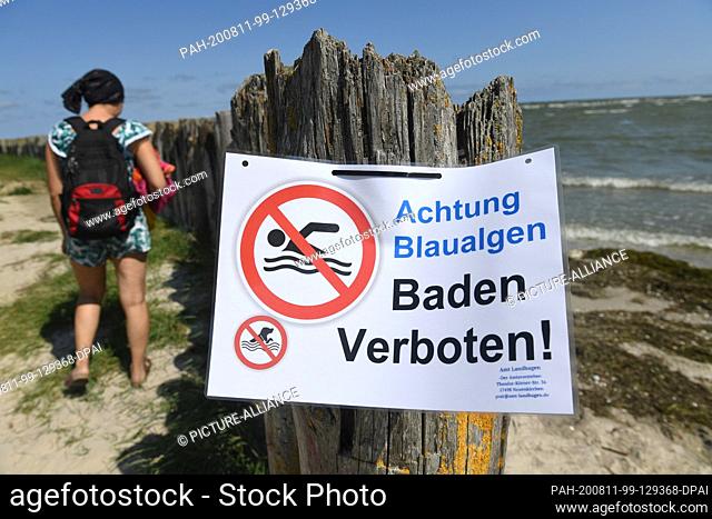 11 August 2020, Mecklenburg-Western Pomerania, Wampen: A sign prohibits bathing in the Bodden near Wampen (Vorpommern-Greifswald) because blue-green algae have...