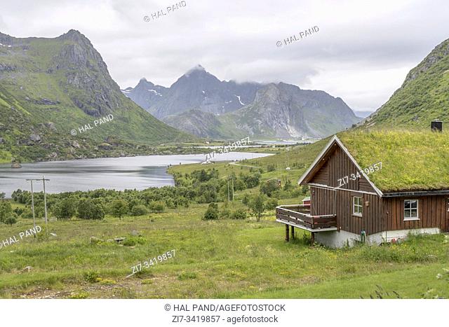 Arctic circle fjord landscape with grass roof and green valley, shot under bright cloudy light near Napp, Lofoten, Norway
