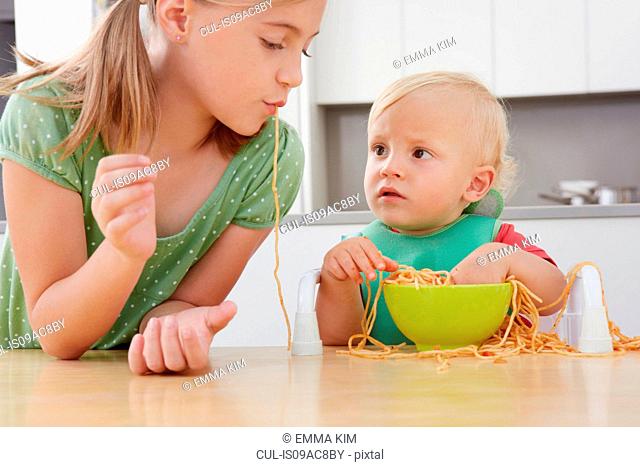 Girl and toddler playing with spaghetti